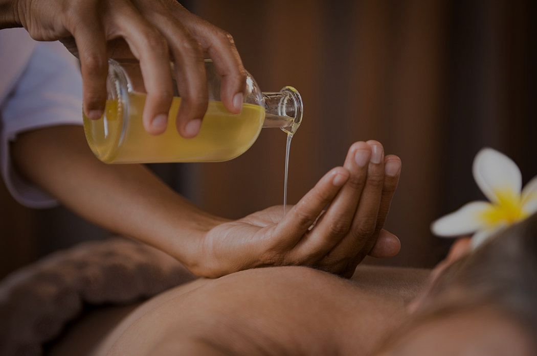 Close-up of hands pouring massage oil onto a client's back