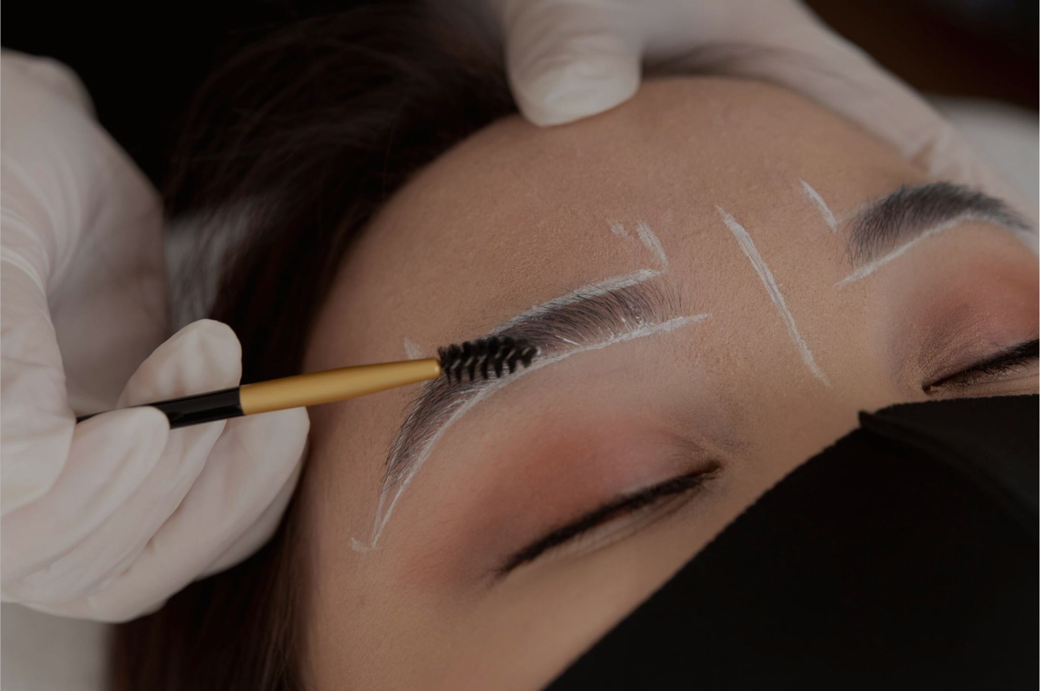 Technician applying eyebrow and lash tinting to a client